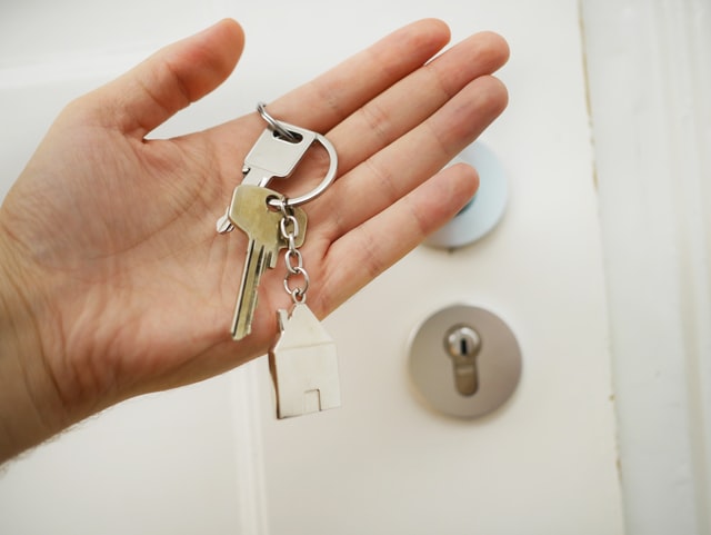 hand holding house keys with a home keyring